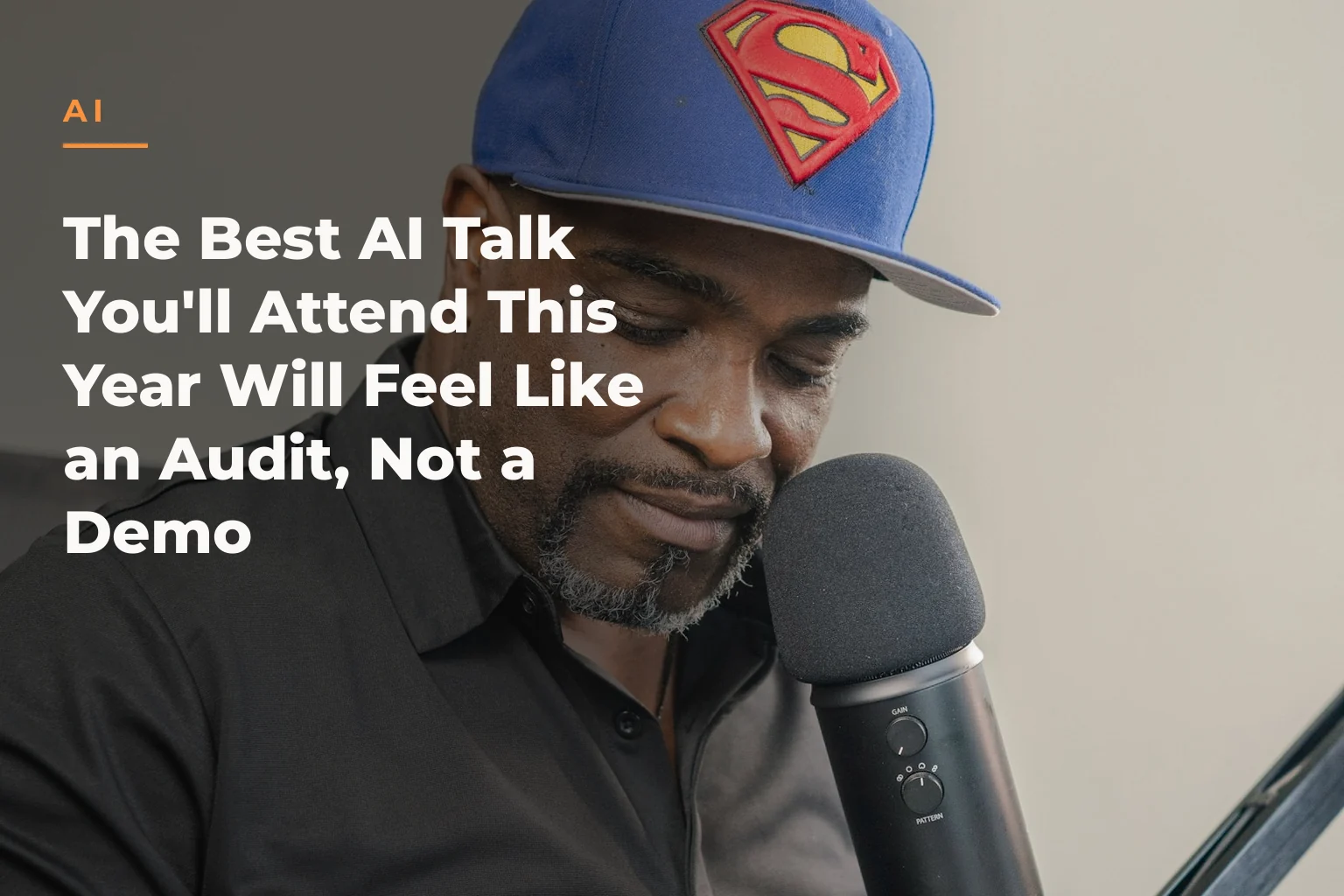 Atiba de Souza wearing a blue baseball cap with a Superman logo, seated in front of a microphone. The cover reads: AI The Best AI Talk You'll Attend This Year Will Feel Like an Audit, Not a Demo